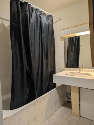 a bathroom with a black shower curtain and a sink at Appartement F2 à 50 m de la plage in Nice