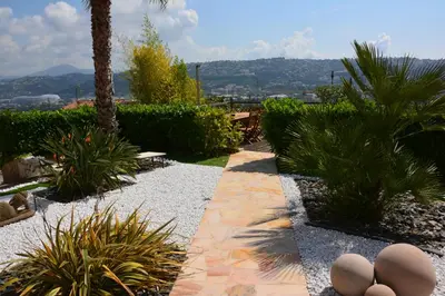a garden with a pathway with statues and palm trees at Villa ZEN in Saint-Laurent-du-Var