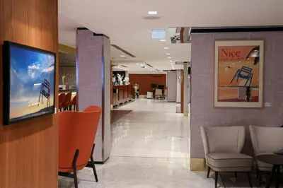 a lobby of a hospital with chairs and a tv at Le Meridien Nice in Nice