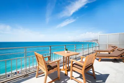 a balcony with a table and chairs and the ocean at Le Meridien Nice in Nice