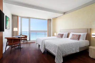 a hotel room with a bed and a desk and a window at Le Meridien Nice in Nice