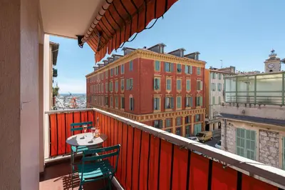 a balcony with a table and chairs on a building at Port, vue mer et confort et parking in Nice