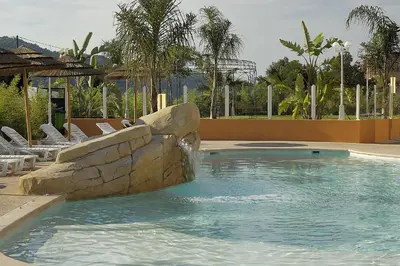 a swimming pool with a waterfall in a resort at Appart Hotel Lou Castelet in Carros