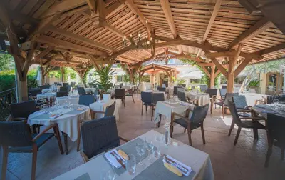 a restaurant with white tables and chairs and a wooden ceiling at Appart Hotel Lou Castelet in Carros