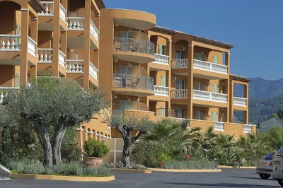a large apartment building with trees in a parking lot at Appart Hotel Lou Castelet in Carros