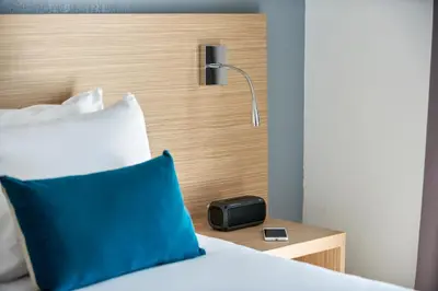 a bed with a blue pillow and a clock on a night stand at Aparthotel Adagio Access Nice Magnan in Nice