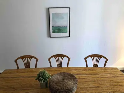 a wooden table with four chairs and a picture on the wall at Lovely large familial apartment in central Nice, ten minutes walk to the beach! in Nice
