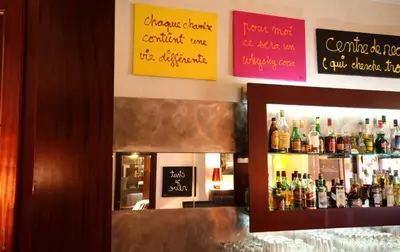 a bar with a bunch of bottles of alcohol at Le Windsor, Jungle Art Hotel in Nice