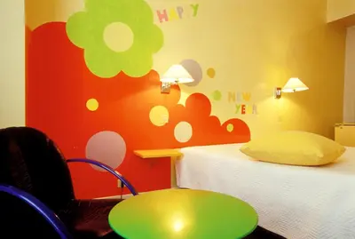 a bedroom with two beds and a table and a flower wall at Le Windsor, Jungle Art Hotel in Nice