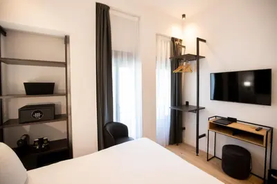 a bedroom with a bed and a desk and a television at Hotel Saint Georges in Nice