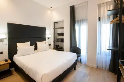 a bedroom with a large white bed and a chair at Hotel Saint Georges in Nice