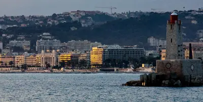 a lighthouse in the water in front of a city at Goldstar Apartments & Suites in Nice