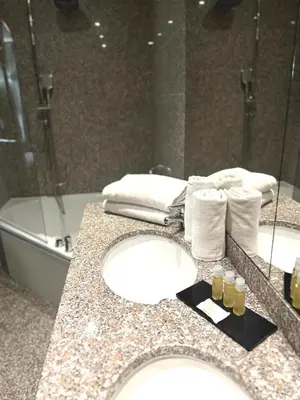 a bathroom with a counter with two sinks and a tub at Goldstar Apartments & Suites in Nice