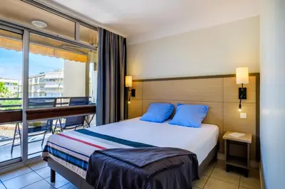 a hotel room with a bed and a balcony at Résidence Pierre & Vacances Heliotel Marine in Saint-Laurent-du-Var