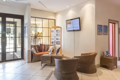a lobby with a couch and chairs and a tv at Résidence Pierre & Vacances Heliotel Marine in Saint-Laurent-du-Var