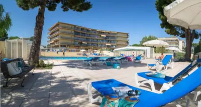 a pool with chairs and tables and a building at Résidence Pierre & Vacances Heliotel Marine in Saint-Laurent-du-Var