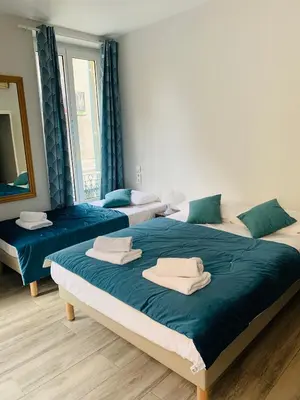 three beds in a room with blue and white at Hotel le Nice Etoile in Nice