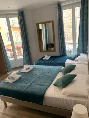 two beds in a room with a mirror and windows at Hotel le Nice Etoile in Nice