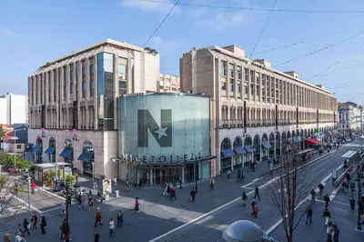 a busy city street with people walking in front of buildings at Hotel le Nice Etoile in Nice