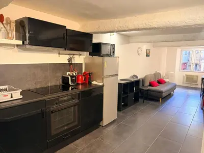 a kitchen with a refrigerator and a couch in a room at La Rose: Charming 2-room apartment in the heart of Nice - 3-min. from the beach in Nice