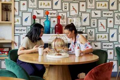 two women sitting at a table looking at a cell phone at Villa Bougainville by Happyculture in Nice