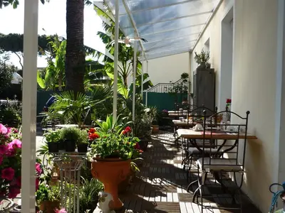 a patio with tables and chairs and potted plants at Logis Hôtel Villa Victorine in Nice