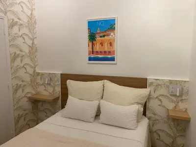 a bed with white pillows and a picture on the wall at Logis Hôtel Villa Victorine in Nice