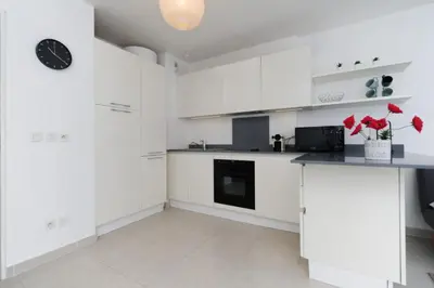 a white kitchen with white cabinets and a black clock at Mini suite Othello - Five Stars Holiday House in Nice