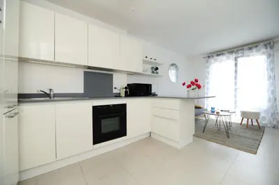 a white kitchen with white cabinets and a table at Mini suite Othello - Five Stars Holiday House in Nice