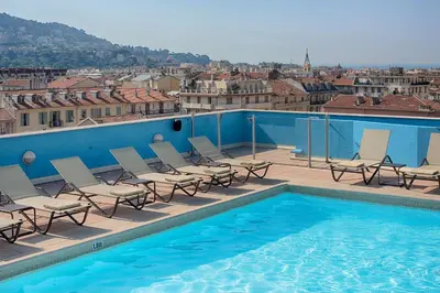a pool with chairs and a view of a city at NH Nice in Nice