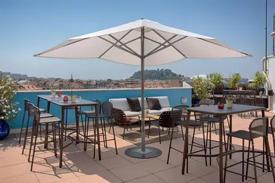 a patio with tables and chairs and an umbrella at NH Nice in Nice