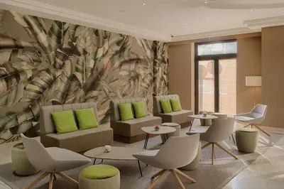 a waiting room with green pillows and tables and chairs at NH Nice in Nice