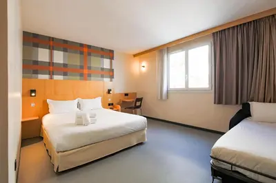 a hotel room with two beds and a desk at easyHotel Nice Old Town in Nice