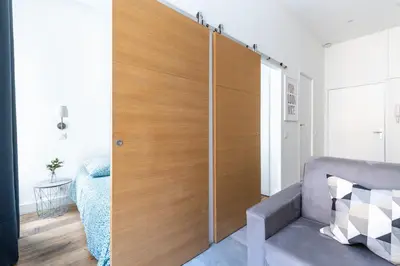 a bedroom with a wooden closet with a bed at 1 CASSINI - Magnifique 2 pièces place Garibaldi - Balcon in Nice