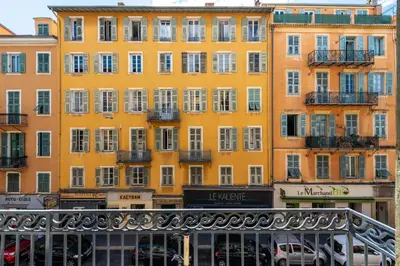 a yellow building with white windows and balconies at 1 CASSINI - Magnifique 2 pièces place Garibaldi - Balcon in Nice