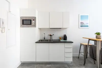 a white kitchen with a sink and a microwave at 1 CASSINI - Magnifique 2 pièces place Garibaldi - Balcon in Nice