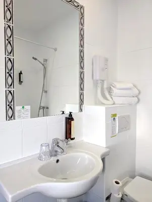 a white bathroom with a sink and a mirror at H33 Hôtel in Nice