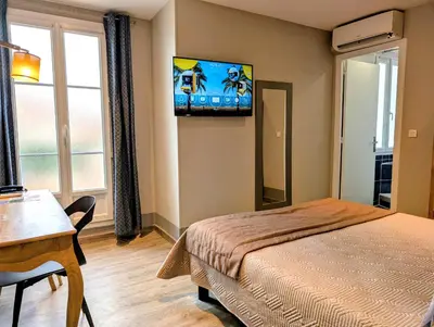 a bedroom with a bed and a flat screen tv at H33 Hôtel in Nice