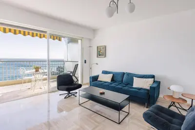 a living room with a blue couch and a table at French Riviera - 3 pièces, vue mer et piscine in Villefranche-sur-Mer