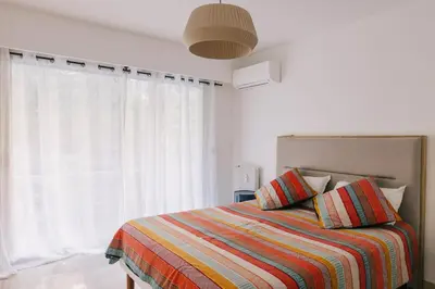 a bedroom with a bed with a colorful blanket and a window at French Riviera - 3 pièces, vue mer et piscine in Villefranche-sur-Mer