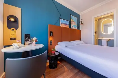 a room with a bed and a table and a white bed at ibis Nice Centre Notre Dame in Nice