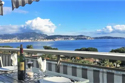 a table with a bottle of wine on a balcony with the ocean at 2P NEUF vue Promenade des Anglais / Tram 10min centre in Nice