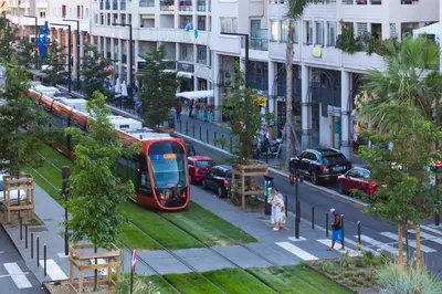 a red tram on a city street with cars at #23 Henry IV Vue Panoramique Mer AC & Bright in Nice