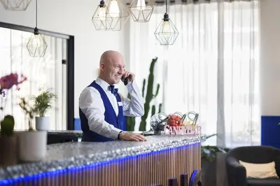 a man talking on a cell phone at a bar at Hôtel Locarno Nice in Nice