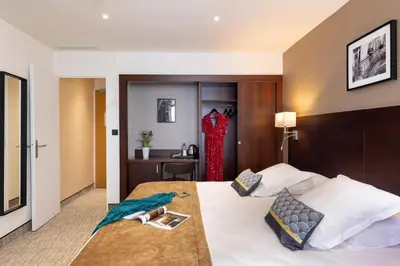 a hotel room with a bed and a desk at Hôtel Locarno Nice in Nice