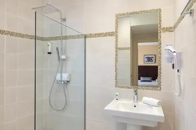 a bathroom with a shower and a sink and a mirror at Hôtel Locarno Nice in Nice