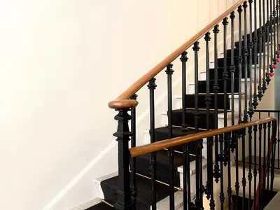 a staircase with black railings and a wooden hand railing at Villa Berlioz in Nice