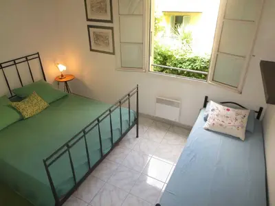 a small bedroom with a bed and a window at Vieux Nice, grand 2P sur jardins, parking, calme, soleil in Nice