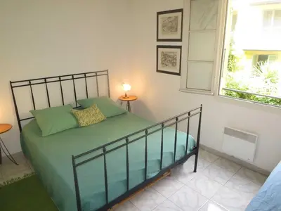 a bedroom with a bed with green sheets and a window at Vieux Nice, grand 2P sur jardins, parking, calme, soleil in Nice
