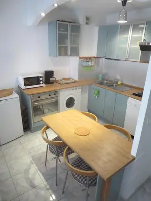 a kitchen with a wooden table and chairs in it at Vieux Nice, grand 2P sur jardins, parking, calme, soleil in Nice